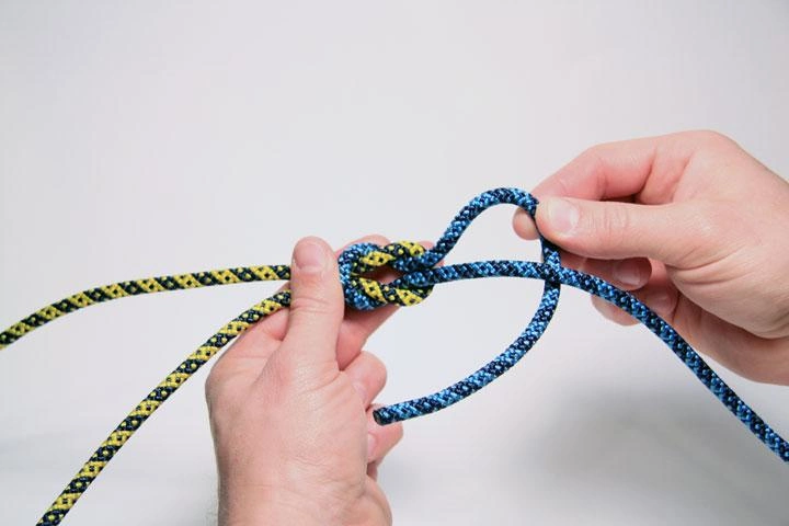 Square knot being tied with two ropes in hands